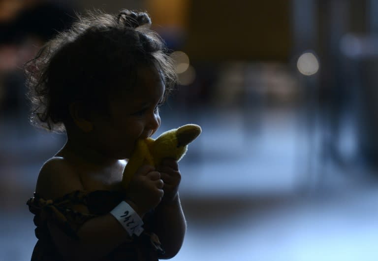 A child plays as refugees wait to be processed at a police first registration point in Passau, southern Germany, on July 23, 2015