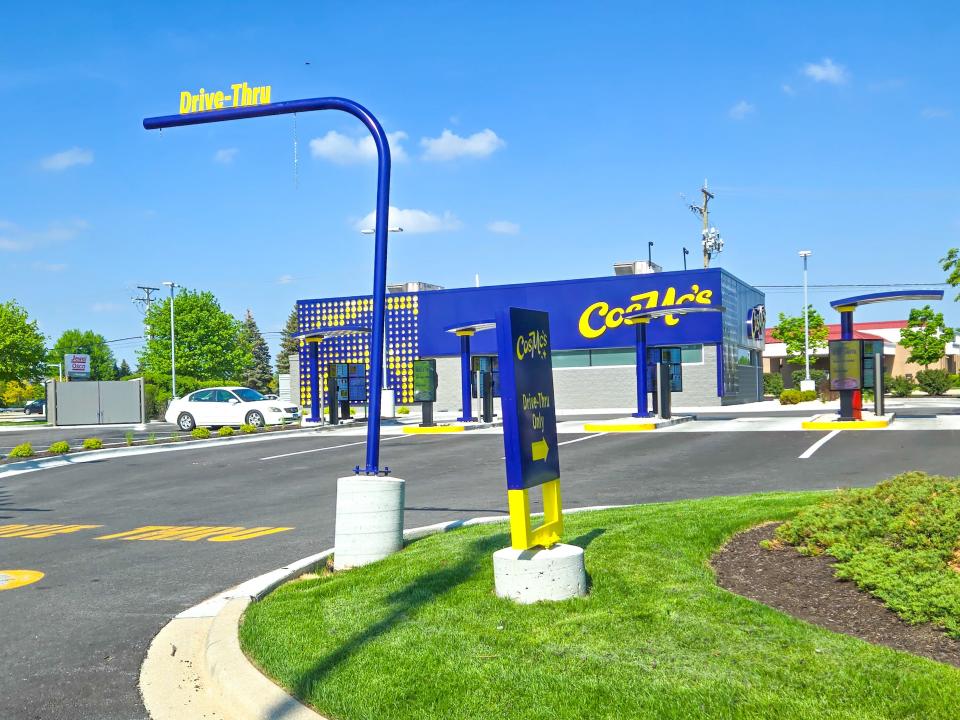 Blue and yellow CosMc's building with four drive-thru lanes and a pole with yellow lettering that says "drive-thru"