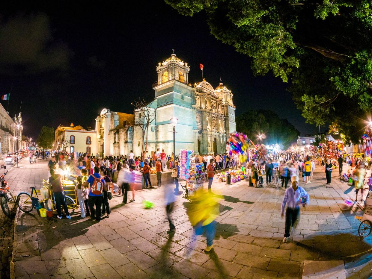 Cathedral of Our Lady of the Assumption, Oaxaca, Mexico at night with people walking around on the streets, lively atmosphere, fish-eye lens