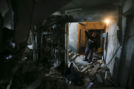 A man shows a staircase at a multi-storey block of flats damaged by shelling in Yenakieve town, northeast from Donetsk, February 2, 2015. REUTERS/Maxim Shemetov