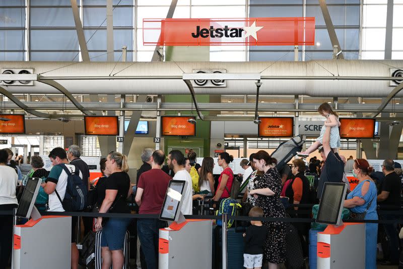 Travelers wait in line at a Jetstar Airways counter at Kingsford Smith International Airport in Sydney