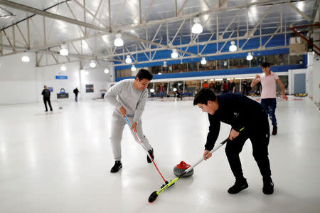 A refugee family from Afghanistan sweeps on the ice as they are introduced to the sport of curling at the Royal Canadian Curling Club during an event put on by the "Together Project", in Toronto, March 15, 2017. REUTERS/Mark Blinch