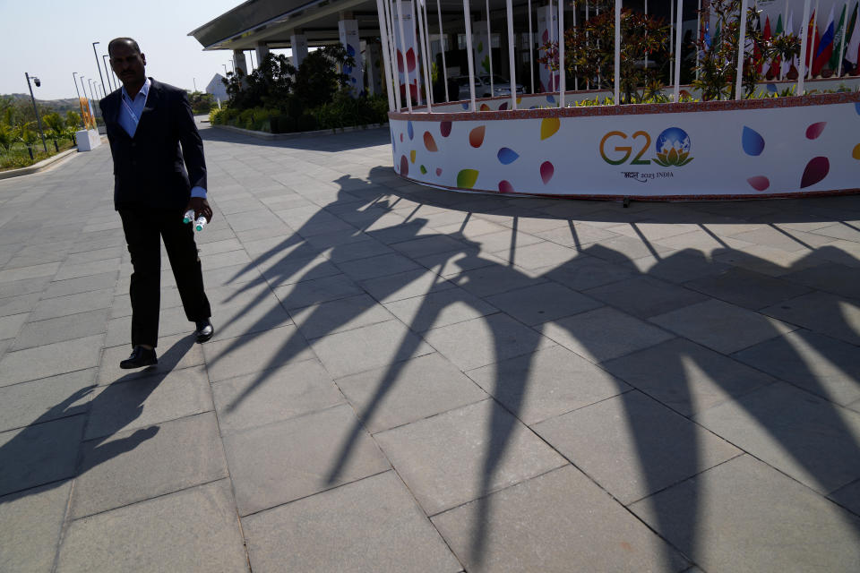 A security official walks past the shadows of the flags of participating countries displayed at the venue of G-20 financial conclave on the outskirts of Bengaluru, India, Wednesday, Feb. 22, 2023. Top financial leaders from the Group of 20 leading economies are gathering in the south Indian technology hub of Bengaluru to tackle challenges to global growth and stability. India is hosting the G-20 financial conclave for the first time in 20 years. (AP Photo/Aijaz Rahi)