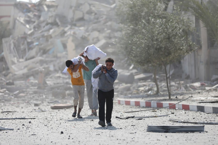 Palestinians walk by the buildings destroyed in the Israeli bombardment on al-Zahra, on the outskirts of Gaza City, Friday, Oct. 20, 2023. (AP Photo/Ali Mahmoud)