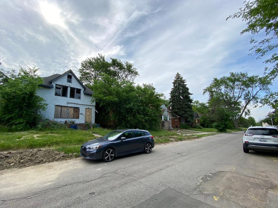 An empty street with boarded up and abandoned homes on it.