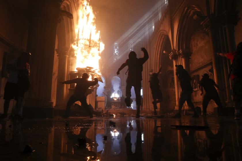 Protesters storm the San Francisco de Borja church, that belongs to Carabineros, Chile's national police force, on the one-year anniversary of the start of anti-government mass protests over inequality in Santiago, Chile, Sunday, Oct. 18, 2020. (AP Photo/Esteban Felix)