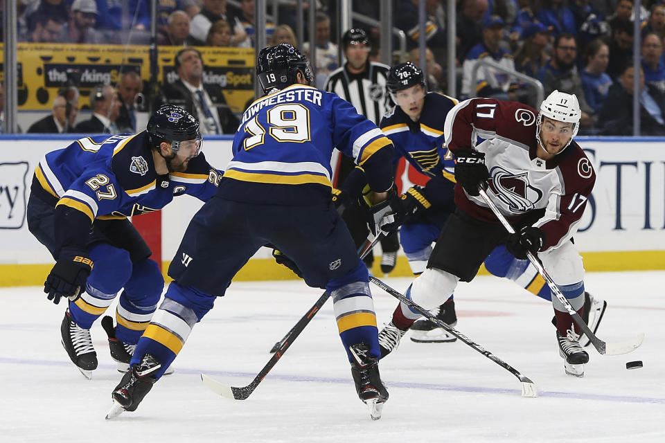 Colorado Avalanche's Tyson Jost, right, looks to get the puck past St. Louis Blues' Jay Bouwmeester (19) and Alex Pietrangelo (27) during the second period of an NHL hockey game Monday, Oct. 21, 2019, in St. Louis. (AP Photo/Scott Kane)