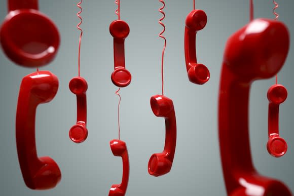 Red phone receivers hanging by their cords.