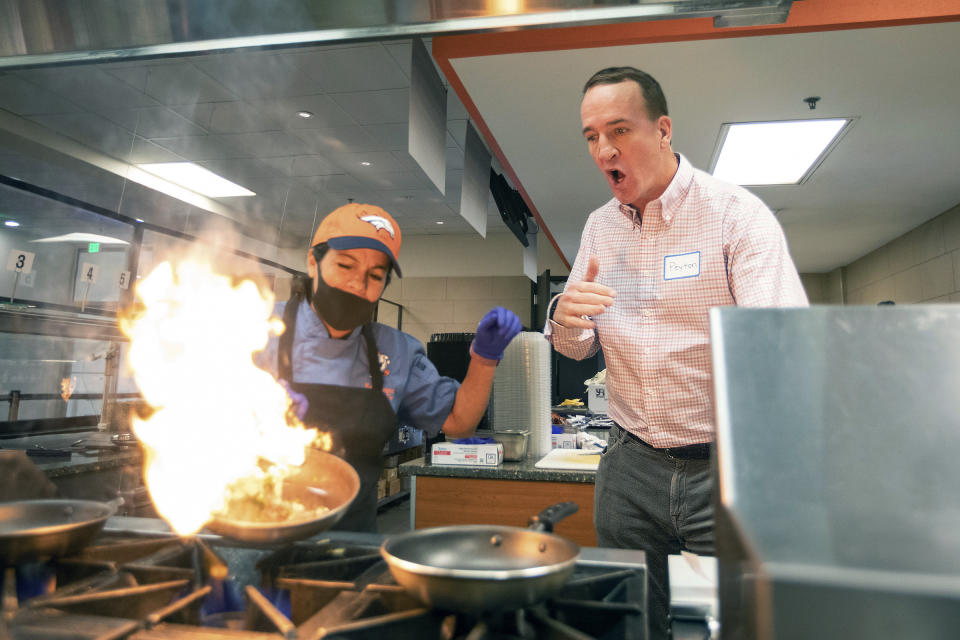 During filming for the Denver Broncos' 2021 schedule release video, former quarterback and current "intern" Peyton Manning tries his hand at cooking with lead chef Wendy Jaramillo at UCHealth Training Center on Tuesday, May 10, 2021 in Englewood, Colo. Schedule release day has become a competition across the NFL between the social media departments of teams to see whose video creates the biggest impression.(Ben Swanson/Denver Broncos via AP)