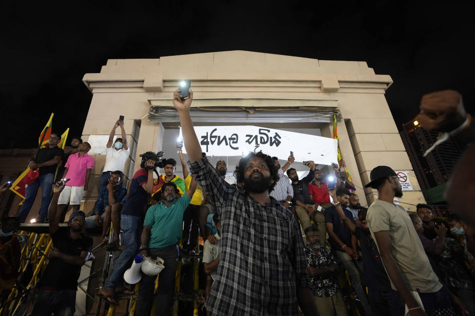 Sri Lankans hold up their mobile phone torches during a vigil condemning police shooting at protesters in Rambukkana, 90 kilometers (55 miles) northeast of Colombo, at a protest outside the president's office in Colombo, Sri Lanka, Tuesday, April 19, 2022. Sri Lankan police opened fire Tuesday at a group of people protesting new fuel price increases, killing one and injuring 10 others, in the first shooting by security forces during weeks of demonstrations over the country's worst economic crisis in decades. (AP Photo/Eranga Jayawardena)