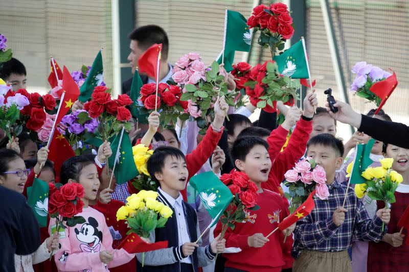 Children holding Chinese and Macau flags get ready before Chinese President Xi Jinping's arrival at Macau International Airport in Macau