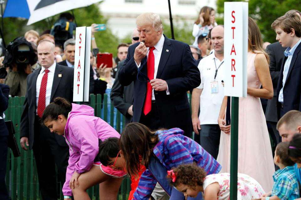 Trump blows a whistle to start the White House Easter Egg Roll alongside his wife, Melania, and his youngest son, Barron.