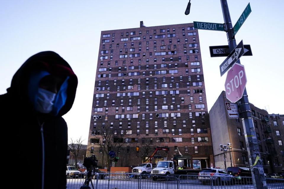 A person walks past an apartment building that suffered the city’s deadliest fire in three decades, in the Bronx, Tuesday, Jan. 11, 2022. (AP Photo/Matt Rourke)