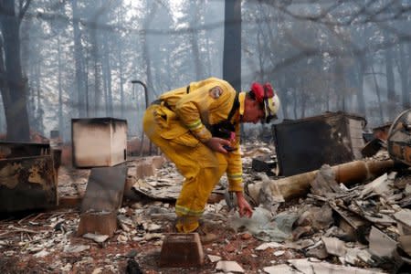 Cal Fire firefighter Stewart Morrow inspects a house destroyed by the Camp Fire in Paradise, California, U.S., November 14, 2018.  REUTERS/Terray Sylvester