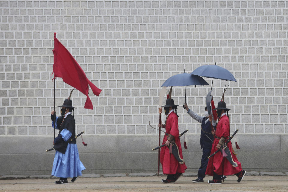 Imperial guards wearing face masks to help protect against the spread of the coronavirus move during rain at the Gyeongbok Palace in Seoul, South Korea, Sunday, Nov. 1, 2020. (AP Photo/Ahn Young-joon)
