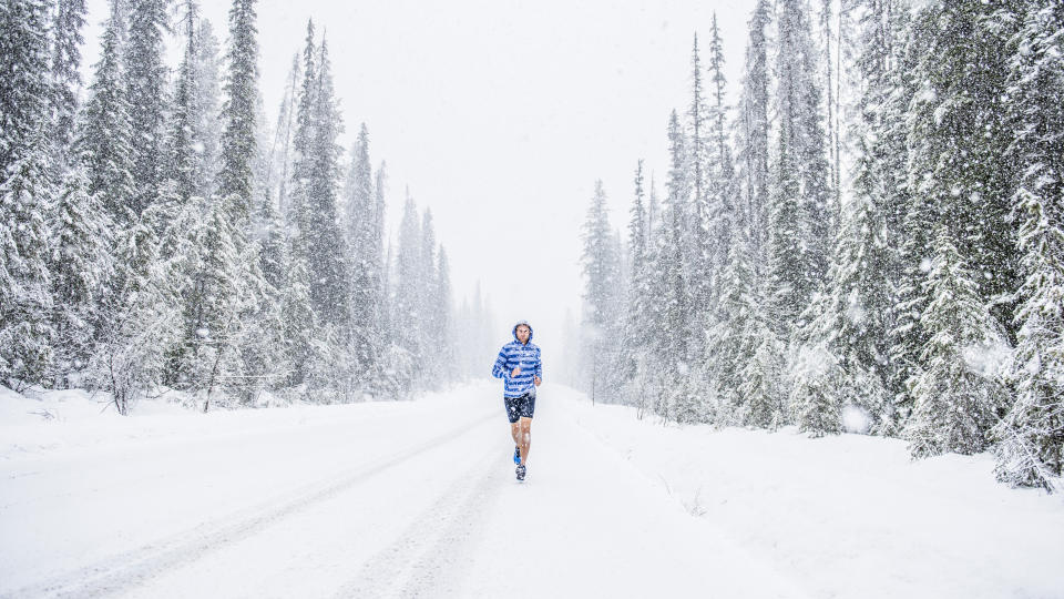 A man running through pine trees in the snow