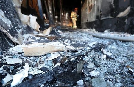 A firefighter stands on debris at a burnt hospital in Miryang, South Korea January 26, 2018. Yonhap via REUTERS