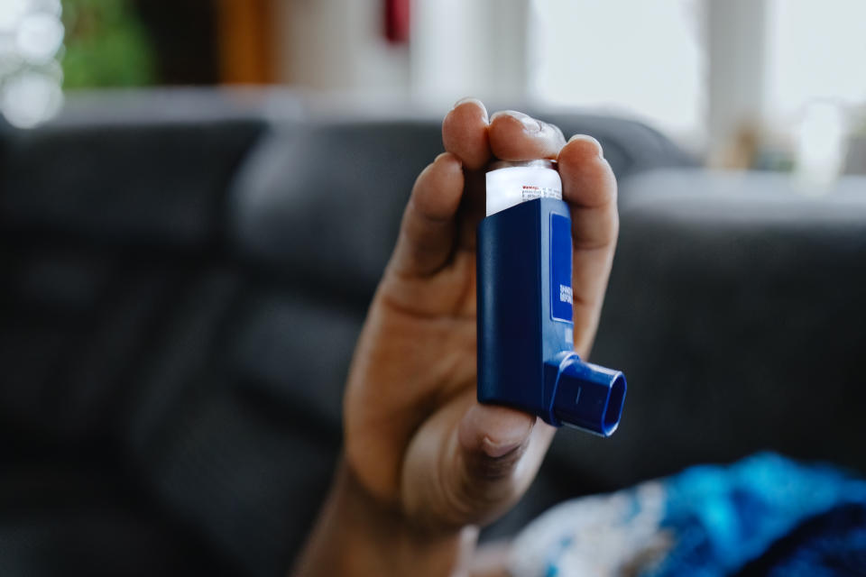 Close-up of unrecognizable black woman sitting on couch holding an asthma inhaler