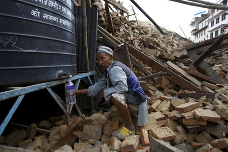 A man fills water from a water tank near a collapsed temple in Kathmandu, Nepal April 26, 2015, a day after a 7.9 magnitude earthquake killed more than 2,400 people and devastated Kathmandu valley. REUTERS/Navesh Chitrakar