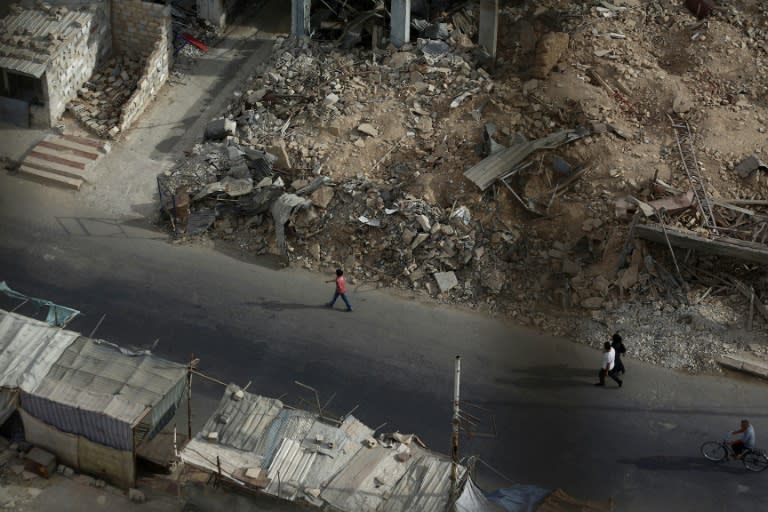 Residents walk past the rubble of destroyed buildings on September 16, 2015, in the rebel-held area of Douma, east of the Syrian capital Damascus
