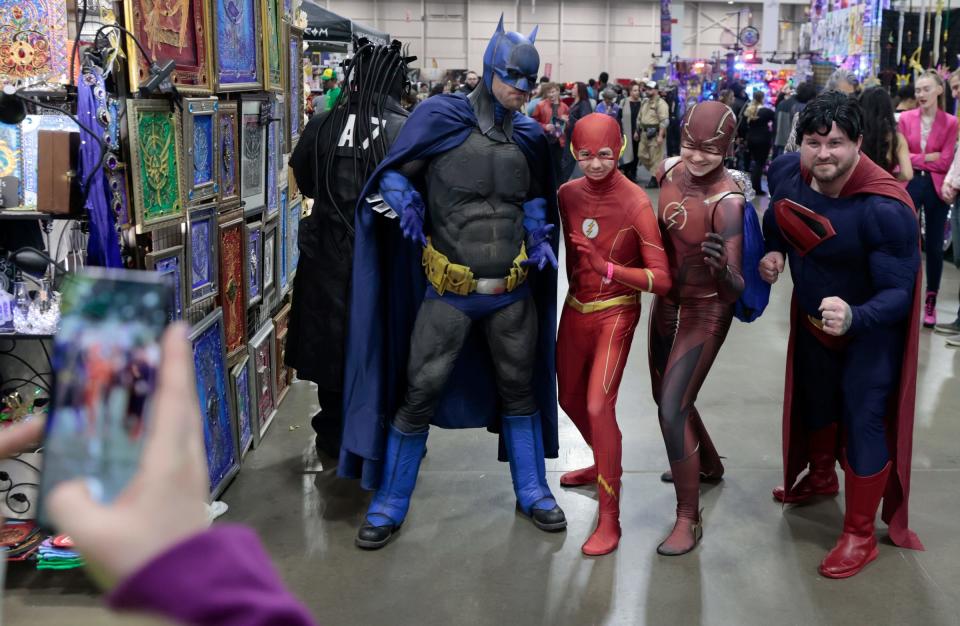 (L to R) Brothers Ben and Mike Kaptur both who love The Flash pose for a photo on their iPhone with Batman and Superman cosplayers during the Motor City Comic Con at the Suburban Collection Showplace in Novi on Saturday, November 11, 2023.
