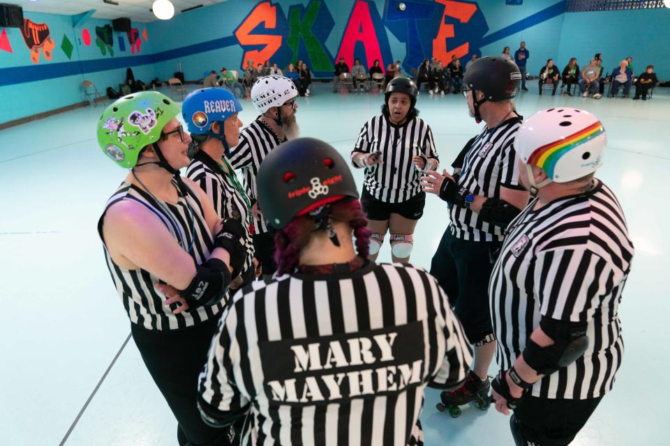 Roller derby referees huddle to have an official review of a previous jam to see if there were any penalties or scoring mishaps during Saturday's bout with the Capital City Crushers and Salina Sirens.