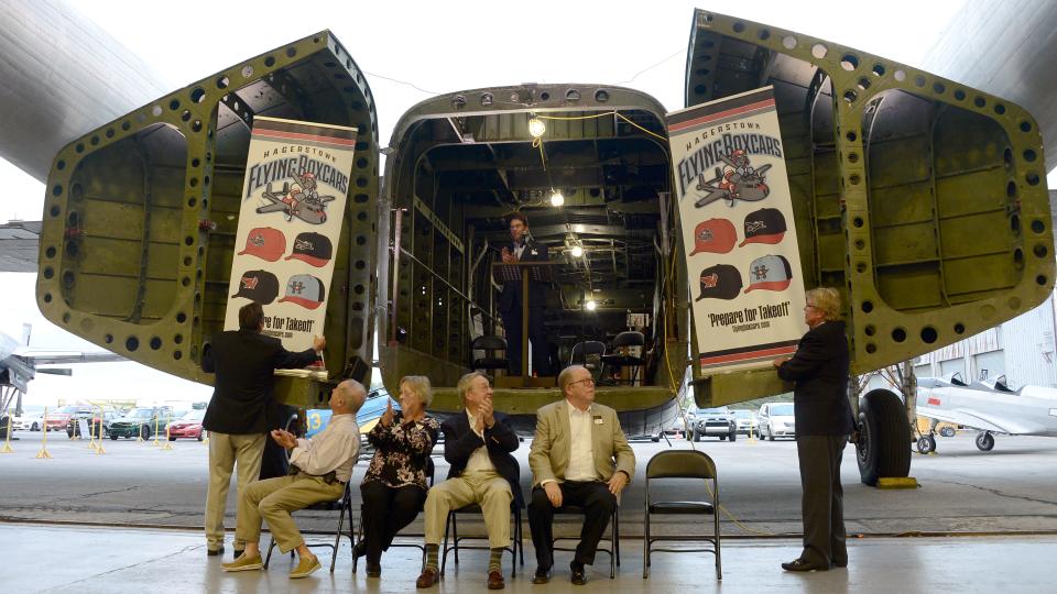 The owners of Downtown Baseball LLC watch as the logo of the Hagerstown Flying Boxcars is unveiled during a ceremony Wednesday night at the Hagerstown Aviation Museum north of the city. Chuck Domino, president of Domino Management and Consulting LLC, standing left, and Frank Boulton, a member of the ownership group, standing right, reveal the logos after a countdown from Team Manager David Blenkstone, standing in the back of the plane. The rest of Downtown Baseball's owners are, seated from left, Don Bowman, Linda Ebersole, James Holzapfel and Howard "Blackie" Bowen.