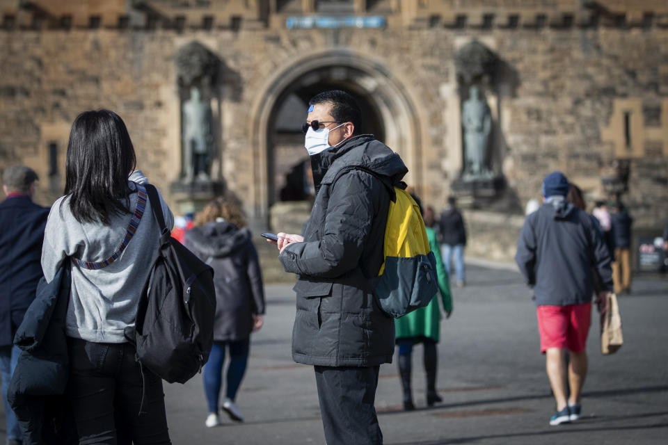 A visitor at Edinburgh Castle wears a protective face mask as the Government's top scientist warmed that up to 10,000 people in the UK are already infected.