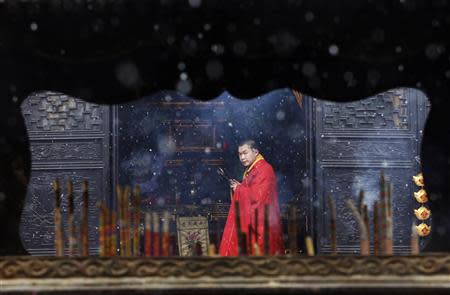 A monk is seen through an incense burner inside a temple as snow falls in Jiaxing, Zhejiang province, in this February 19, 2013 file photo. REUTERS/William Hong/Files (CHINA)