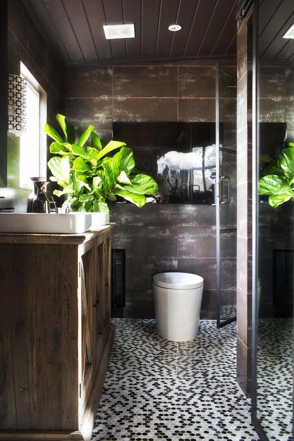 In this undated photo provided by Brian Patrick Flynn/HGTVREMODELS.COM, to add life to dark, well-shaded rooms, designer Brian Patrick Flynn is a fan of the fiddle leaf fig tree which he claims is, "architectural, gender-neutral and a great source for adding graphic shape to a space," as he has done in this bathroom seen here. (AP Photo/Brian Patrick Flynn/HGTVREMODELS.COM, Sarah Dorio)