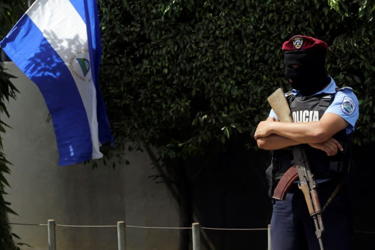 Police officer with face covered stands guard outside the National Judicial Complex building in Managua