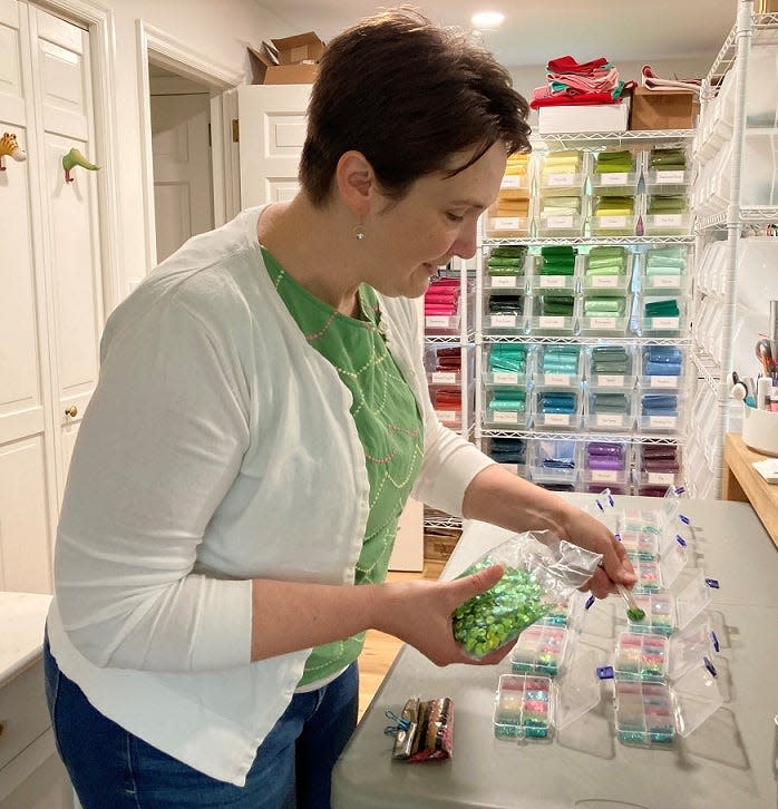 Elizabeth Jones, owner and operator of Poshta Design, sorts beads and sequins, inside her Granville Township work space. Jones designs and assembles kits for people to make hand-made crafts.