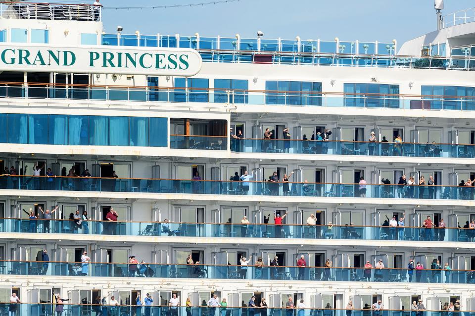 Passengers aboard the Grand Princess celebrate as they arrive in Oakland, Calif., on March 9. The cruise ship, which maintained a holding pattern off the coast for days, carried multiple people who tested positive for COVID-19, a disease caused by the new coronavirus.