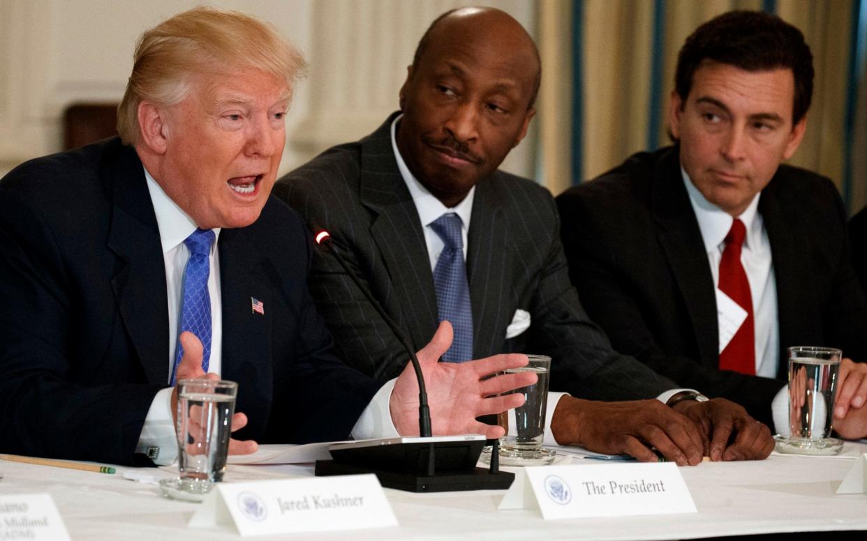 Ken Frazier, seated next to Donald Trump in January, was the first CEO to resign in response to his handling of Charlottesville - AP