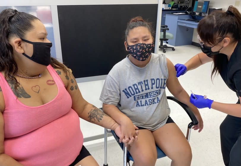 Summer Ariwite holds hands with her niece, Kaycee Moss, who has turned 12, old enough to be vaccinated by Samantha Allen.