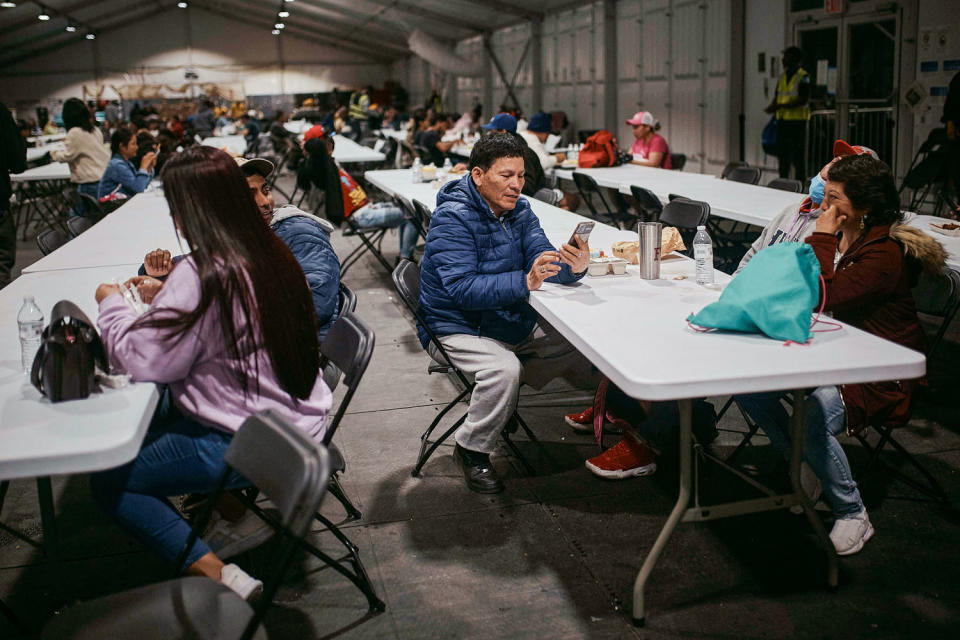 Cesar Anibal Bonilla Estrada, center, checks his phone during dinner time inside of the tent (Andres Kudacki / AP file)