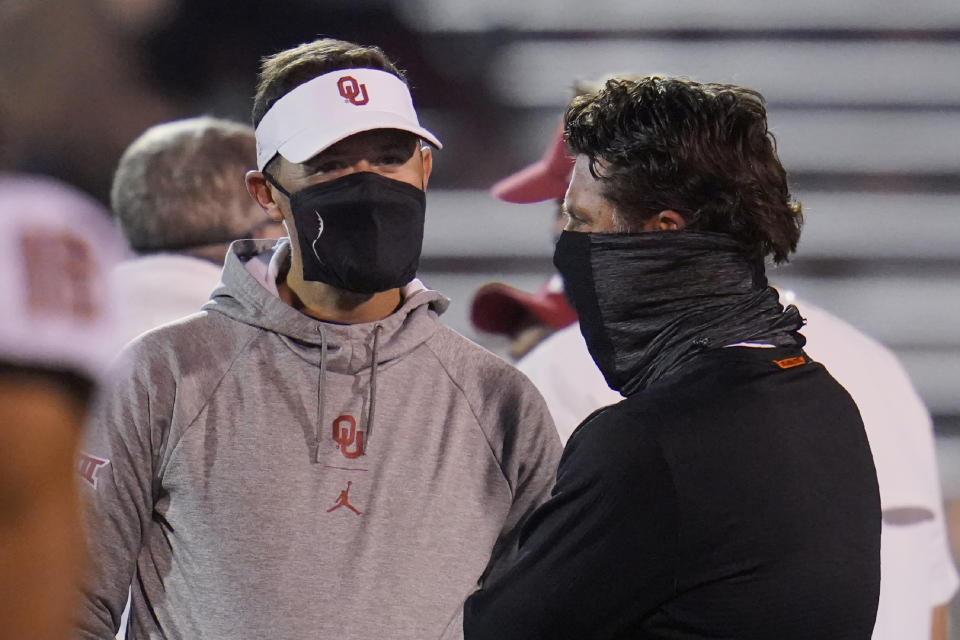 Oklahoma coach Lincoln Riley, left, talks with Oklahoma State coach Mike Gundy before an NCAA college football game in Norman, Okla., Saturday, Nov. 21, 2020. (AP Photo/Sue Ogrocki)