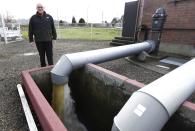 Jack Durney, mayor of Hoquiam, Wash., stands Monday, March 18, 2014 next to a pump that takes groundwater away from neighborhoods in his town, most of which is located on a flood plain. Durney says possible increases in federal flood insurance rates would adversely affect many who live in Hoquiam. (AP Photo/Ted S. Warren)