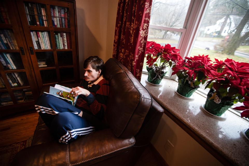 Matt Maillet, 31, reads a children's book at his home in Irvington March 6, 2024. Matt, who has autism and Prader-Willie Syndrome, enjoys going to libraries, and especially likes a music program at the West Harrison Library. The library has informed his aide that because he is an adult, he is not allowed in the children's room at the library. His parents are hoping that the library will change their policy and allow Dan to attend programs in the children's library.