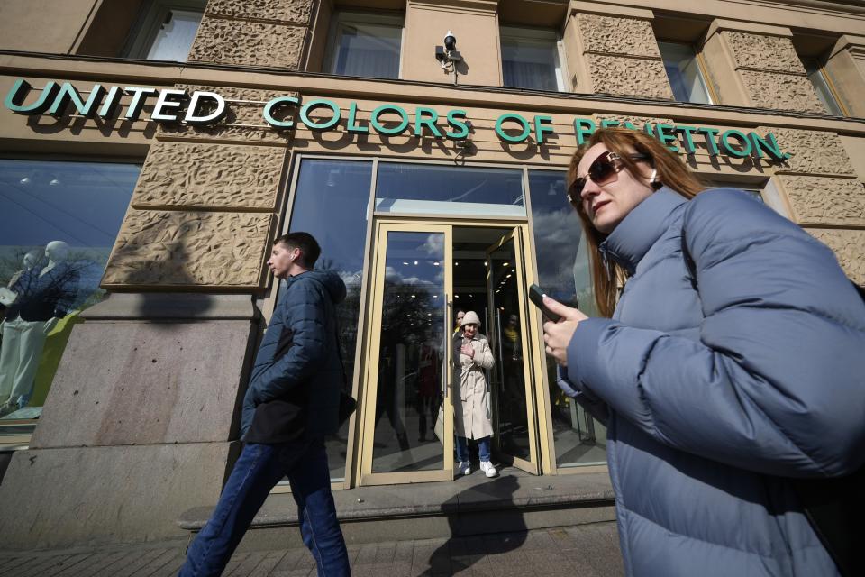 People walk past United Colors of Benetton in St. Petersburg, Russia, Saturday, April 29, 2023. When Russia invaded Ukraine, companies were quick to respond, some announcing they would get out of Russia immediately, others vowed to curtail sales and new investment. More than a year later, it’s clear: Leaving Russia isn't as easy as the first announcements might have made it seem. (AP Photo/Dmitri Lovetsky)