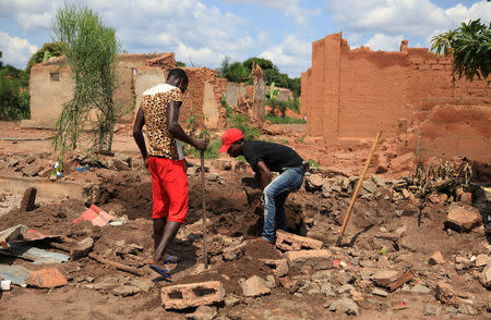 Two men dig up bricks to re-use from a destroyed church in Kapende, a Congolese neighbourhood in Lucapa, Angola, October 19, 2018. REUTERS/Stephen Eisenhammer