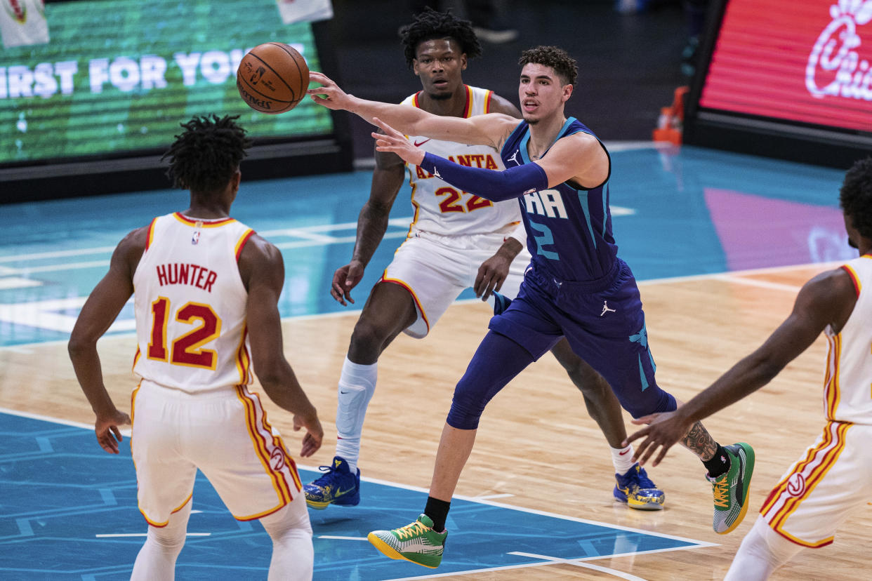 Charlotte Hornets guard LaMelo Ball (2) looks away while passing the ball past Atlanta Hawks forward De'Andre Hunter (12) and forward Cam Reddish (22) during the first half of an NBA basketball game in Charlotte, N.C., Saturday, Jan. 9, 2021. (AP Photo/Jacob Kupferman)