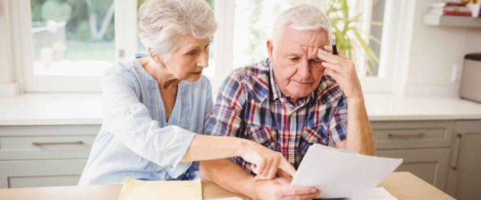 Worried senior couple checking their bills at home