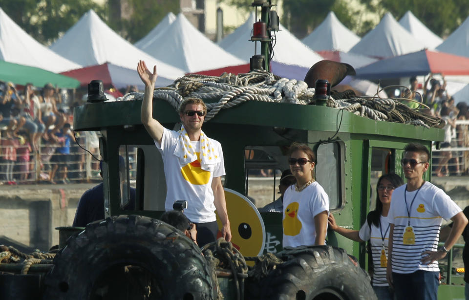 Dutch artist Florentijn Hofman waves to spectators as he and his giant yellow duck art piece arrive in the port of Kaohsiung, Taiwan, Thursday, Sept. 19, 2013. Kaohsiung is the first leg of the Taiwan tour for Hofman's famous 18 meter (59 foot) yellow duck, a gigantic version of the iconic bathtub toy used by children around the world. (AP Photo/Wally Santana)