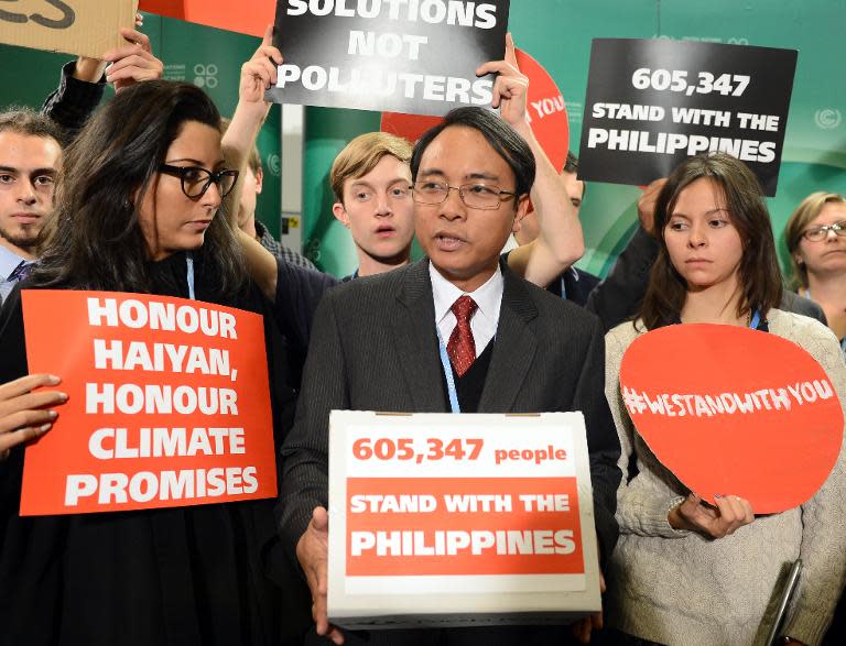 The Philippines' head negotiator Yeb Sano (C) and supporters hold banners while attending the UN Climate Change Conference COP 19 on November 19, 2013 in Warsaw
