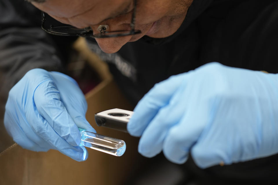 A U.S. Customs and Border Protection agriculture specialist uses a magnifying loupe to inspect a tiny, potentially harmful pest he found in a shipment of imported flowers, at Miami International Airport in Miami, Monday, Feb. 12, 2024. Roughly 90% of flowers imported to the U.S. pass through Miami's airport, most of them arriving from South American countries such as Colombia and Ecuador. (AP Photo/Rebecca Blackwell)