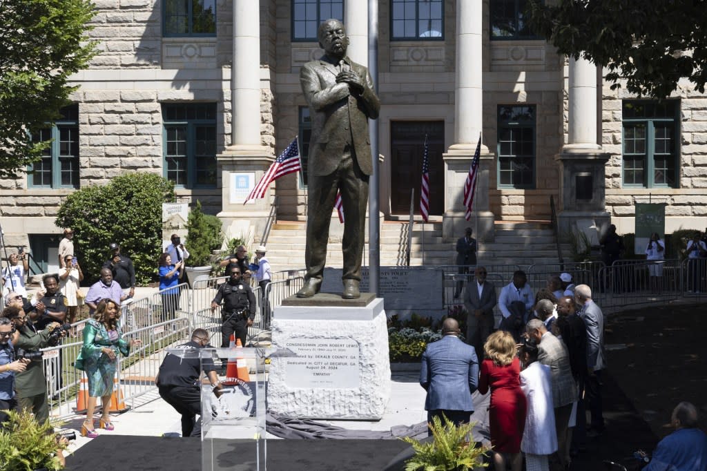 People stand around the statue honoring the late civil rights leader and congressman John Lewis during its unveiling ceremony in Decatur, Ga., on Saturday, Aug 24, 2024. (Steve Schaefer/Atlanta Journal-Constitution via AP)