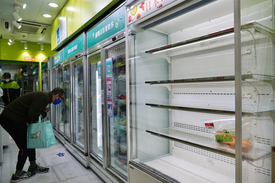 A man wearing a face mask looks for food next to the empty shelves of fruit as residents fear a fresh food shortage at a market in Hong Kong, Monday, Feb. 28, 2022. Hong Kong on Monday reported a record-high 34,466 infections, with health authorities saying that a lockdown has not been ruled out as fatalities continued to climb. (AP Photo/Vincent Yu)