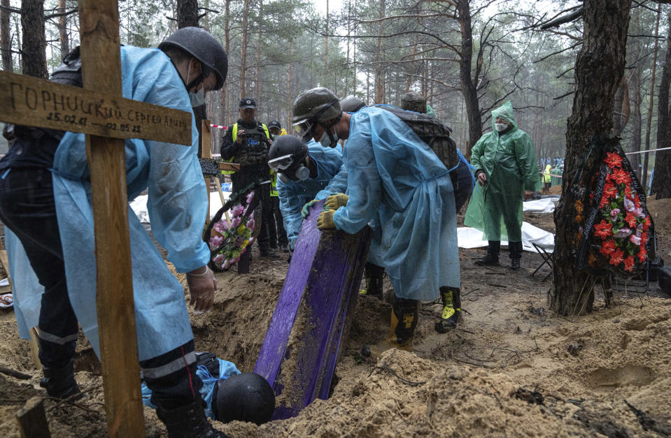 Emergency workers move the body of a civilian during the exhumation, in the recently retaken area of Izium, Ukraine, Friday, Sept. 16, 2022. Ukrainian authorities discovered a mass burial site near the recaptured city of Izium that contained hundreds of graves. It was not clear who was buried in many of the plots or how all of them died, though witnesses and a Ukrainian investigator said some were shot and others were killed by artillery fire, mines or airstrikes. (AP Photo/Evgeniy Maloletka)