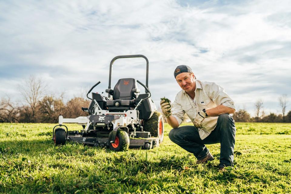 a man kneeling next to a lawn mower